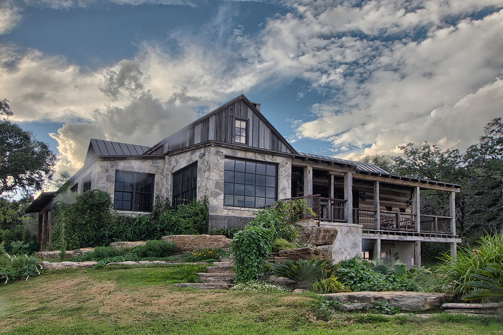 Mid-sized country two-storey grey house exterior in Austin with stone veneer, a gable roof and a metal roof.