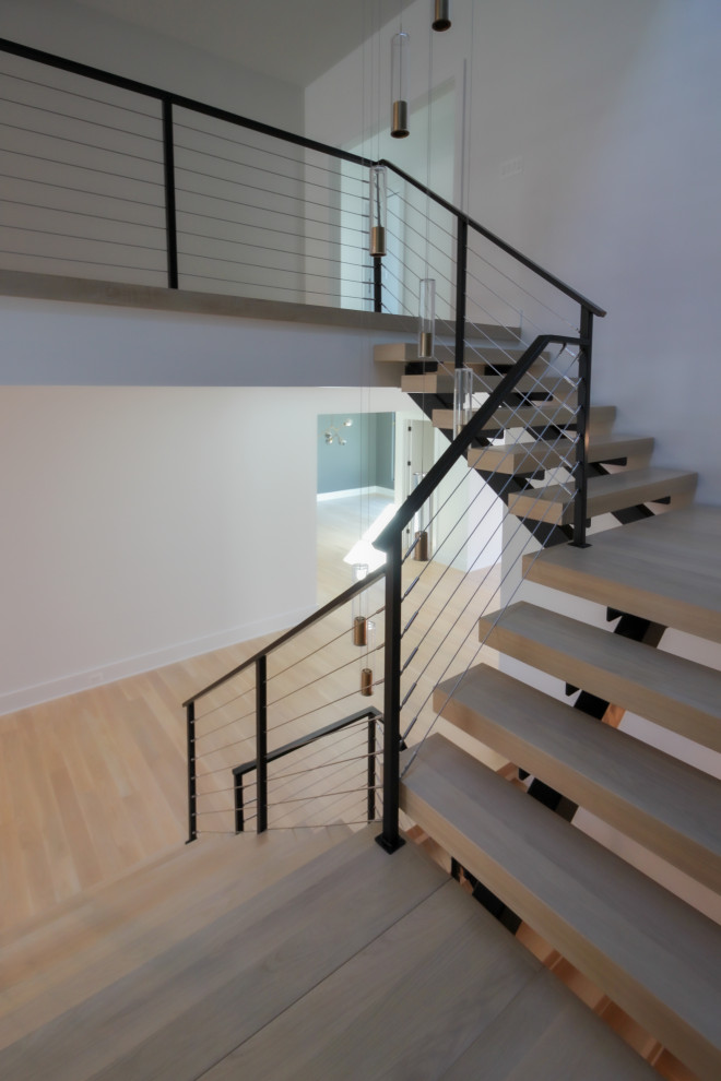 Large eclectic wooden floating metal railing and brick wall staircase photo in DC Metro