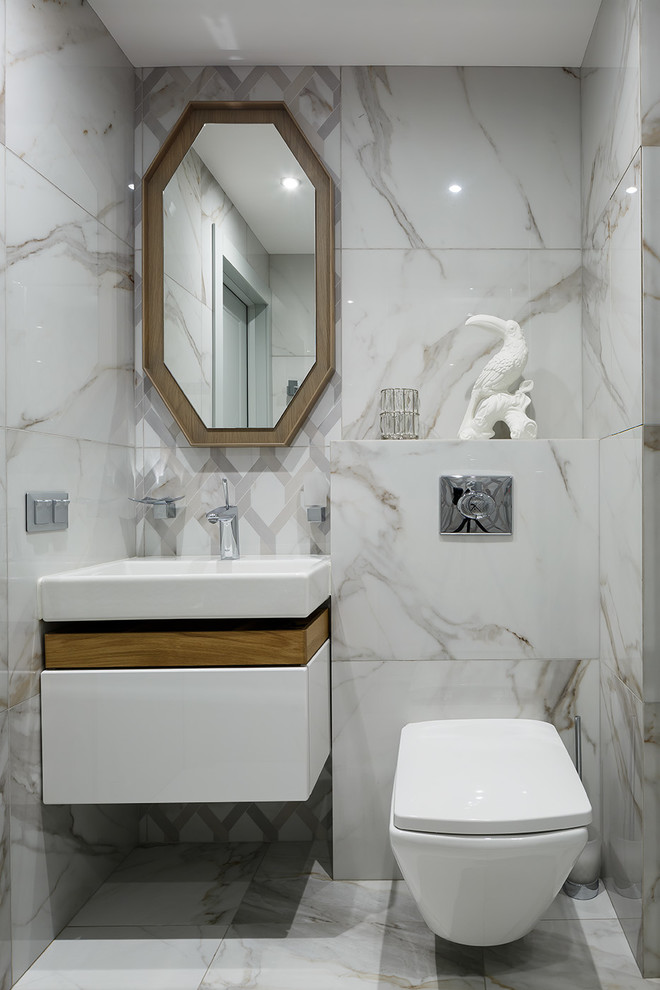Photo of a mid-sized contemporary powder room in Saint Petersburg with a wall-mount toilet, flat-panel cabinets, white cabinets, white tile, white walls, a console sink and white floor.