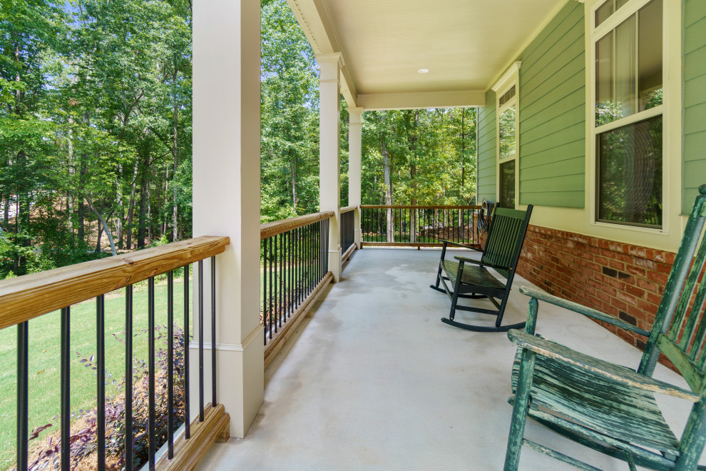 Photo of a large country front yard verandah in Atlanta with concrete pavers, a roof extension and mixed railing.