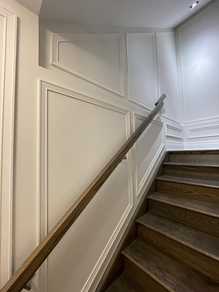 This is an example of a large classic wood straight wood railing staircase in Toronto with wood risers and wainscoting.