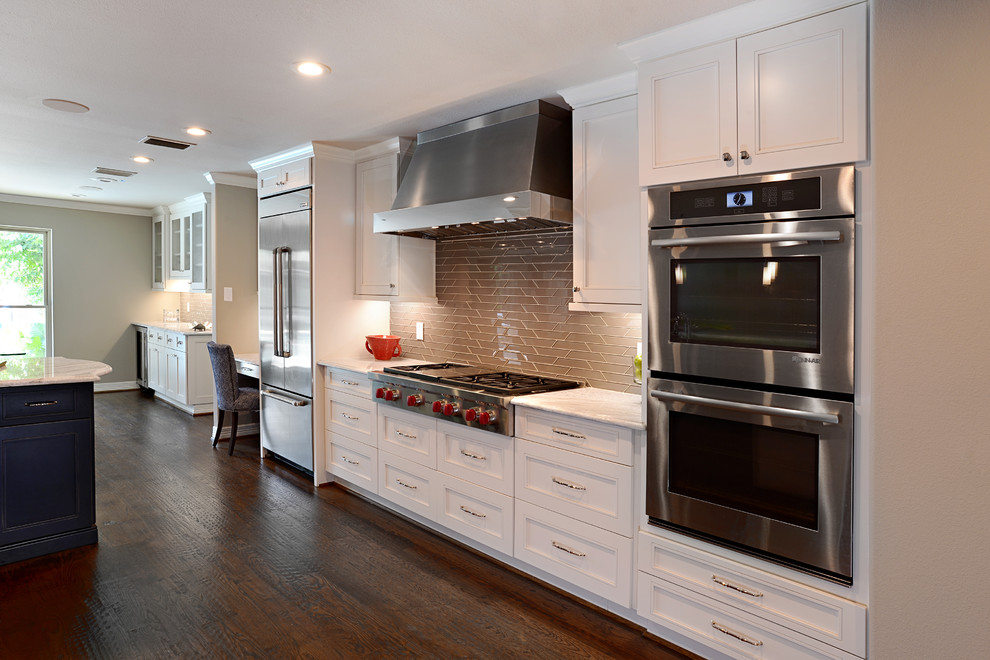 Large transitional single-wall dark wood floor eat-in kitchen photo in Dallas with shaker cabinets, white cabinets, marble countertops, beige backsplash, glass tile backsplash, an island and stainless steel appliances