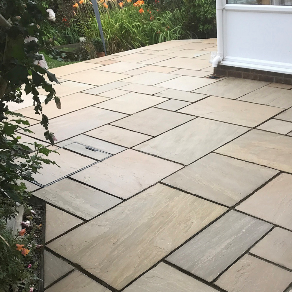 Mid-sized traditional backyard patio in Hertfordshire with natural stone pavers.