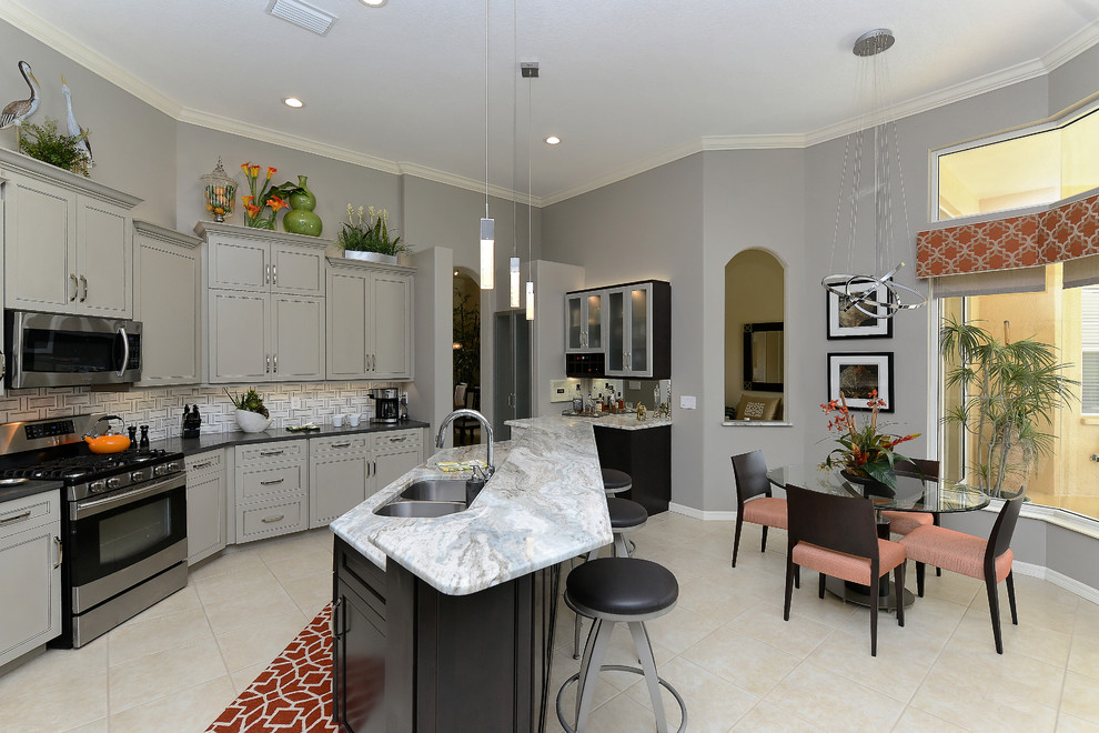 Design ideas for a mid-sized transitional u-shaped eat-in kitchen in Tampa with a double-bowl sink, stainless steel appliances, with island, beaded inset cabinets, grey cabinets, marble benchtops, grey splashback, matchstick tile splashback and ceramic floors.