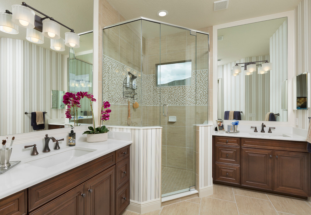 This is an example of a mid-sized traditional master bathroom in Tampa with shaker cabinets, medium wood cabinets, a corner shower, a one-piece toilet, beige tile, glass tile, beige walls, ceramic floors, an undermount sink, engineered quartz benchtops and a hinged shower door.