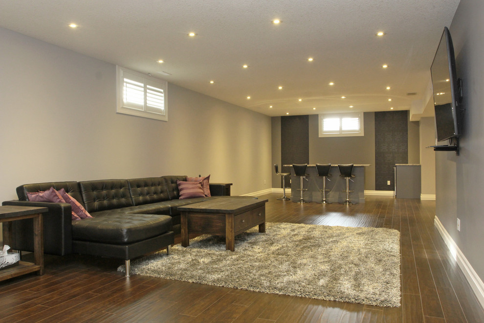 Large transitional look-out medium tone wood floor and brown floor basement photo with gray walls