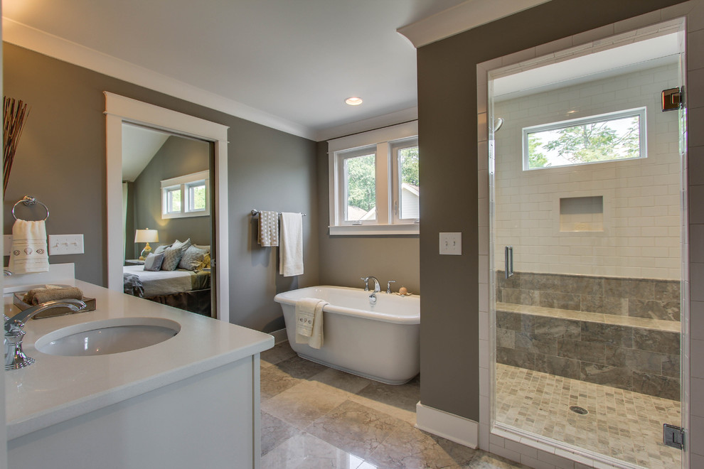 Design ideas for a mid-sized transitional master bathroom in Nashville with an undermount sink, recessed-panel cabinets, white cabinets, engineered quartz benchtops, a freestanding tub, an alcove shower, a two-piece toilet, gray tile, stone tile, grey walls and marble floors.