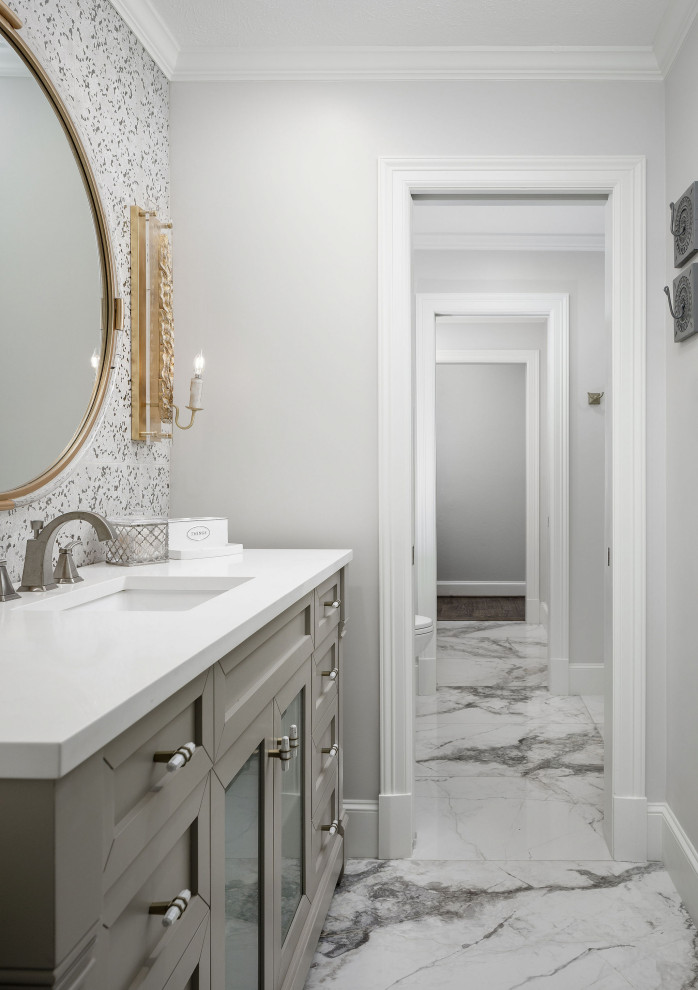 This is an example of a small contemporary bathroom in Dallas with recessed-panel cabinets, grey cabinets, a drop-in tub, a shower/bathtub combo, a two-piece toilet, gray tile, stone tile, grey walls, marble floors, an undermount sink, quartzite benchtops, grey floor, a sliding shower screen, white benchtops, a single vanity, a freestanding vanity and wallpaper.