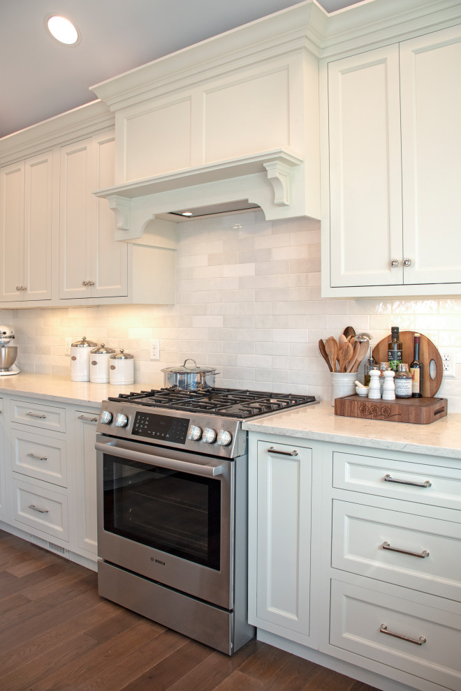 Eat-in kitchen - transitional medium tone wood floor, brown floor and vaulted ceiling eat-in kitchen idea with shaker cabinets, white cabinets, quartz countertops, white backsplash, ceramic backsplash, stainless steel appliances and white countertops