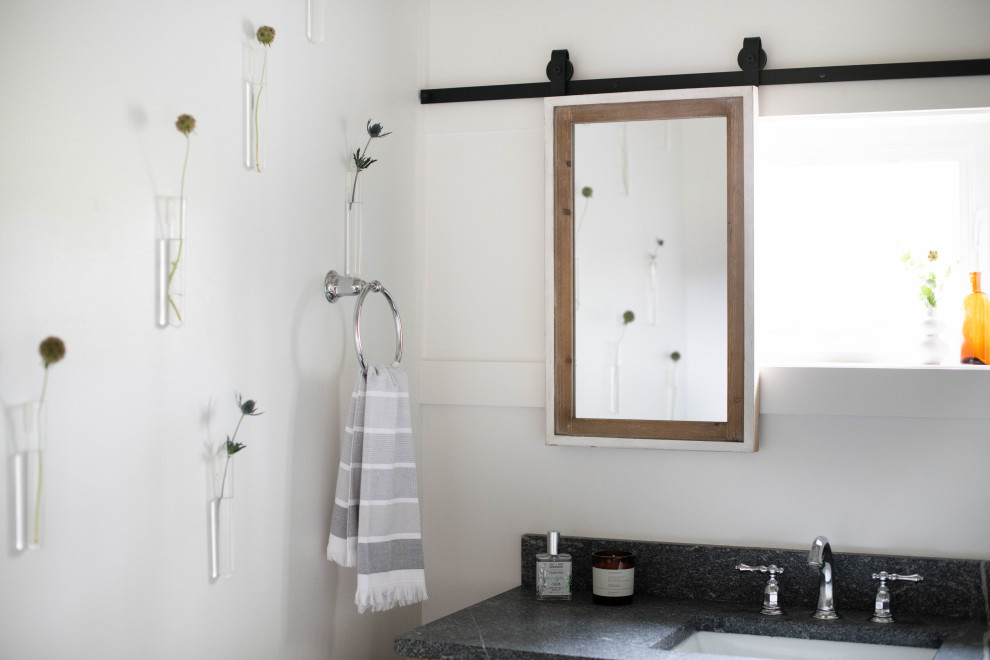 Cette image montre une petite salle de bain rustique en bois clair avec un placard à porte shaker, WC séparés, un carrelage blanc, des carreaux de céramique, un mur blanc, un sol en carrelage de porcelaine, un lavabo encastré, un plan de toilette en granite, un sol gris, une cabine de douche à porte coulissante, un plan de toilette gris, une niche, meuble simple vasque, meuble-lavabo sur pied et un plafond en papier peint.