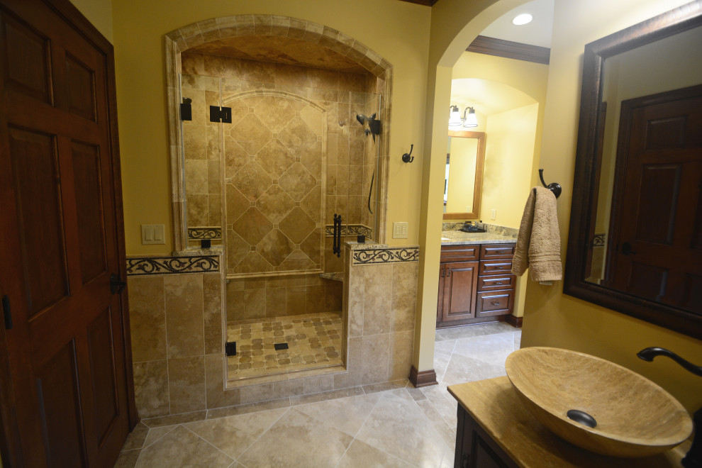 Exemple d'une très grande salle de bain principale méditerranéenne en bois brun avec un placard avec porte à panneau surélevé, une baignoire indépendante, une douche double, WC séparés, un carrelage beige, un mur beige, un sol en calcaire, un lavabo encastré, un plan de toilette en granite, un sol beige, une cabine de douche à porte battante et un banc de douche.