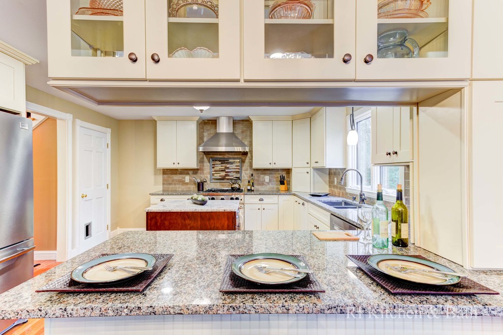 Eat-in kitchen - large transitional u-shaped light wood floor eat-in kitchen idea in Providence with an undermount sink, shaker cabinets, beige cabinets, granite countertops, brown backsplash, porcelain backsplash, stainless steel appliances and an island