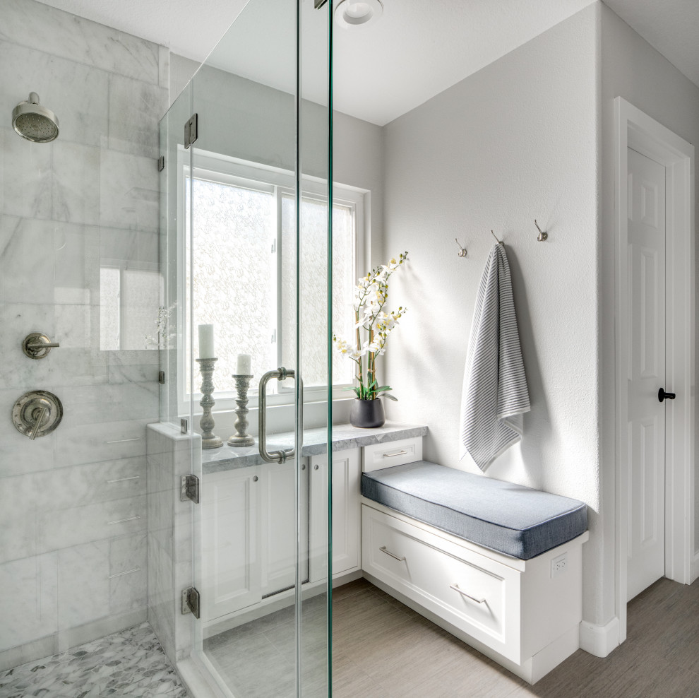 Пример оригинального дизайна: главная ванная комната среднего размера в стиле неоклассика (современная классика) с фасадами в стиле шейкер, белыми фасадами, угловым душем, унитазом-моноблоком, белой плиткой, мраморной плиткой, белыми стенами, полом из керамогранита, врезной раковиной, мраморной столешницей, серым полом, душем с распашными дверями, синей столешницей, сиденьем для душа, тумбой под две раковины и встроенной тумбой