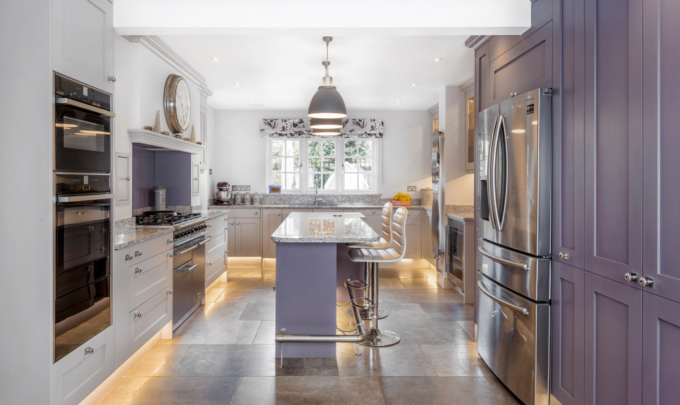 This is an example of a transitional u-shaped kitchen in Other with shaker cabinets, purple cabinets, stainless steel appliances, with island, grey floor and multi-coloured benchtop.