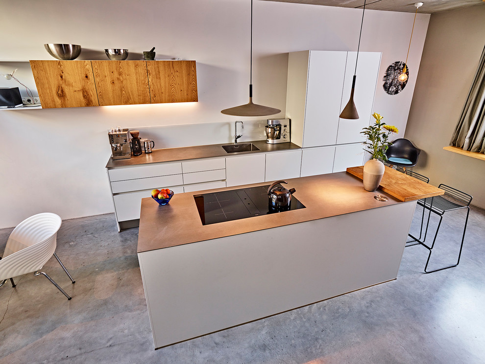 Design ideas for a mid-sized contemporary galley eat-in kitchen in Amsterdam with an integrated sink, flat-panel cabinets, grey cabinets, stainless steel benchtops, white splashback, glass sheet splashback, stainless steel appliances, concrete floors, with island and grey floor.