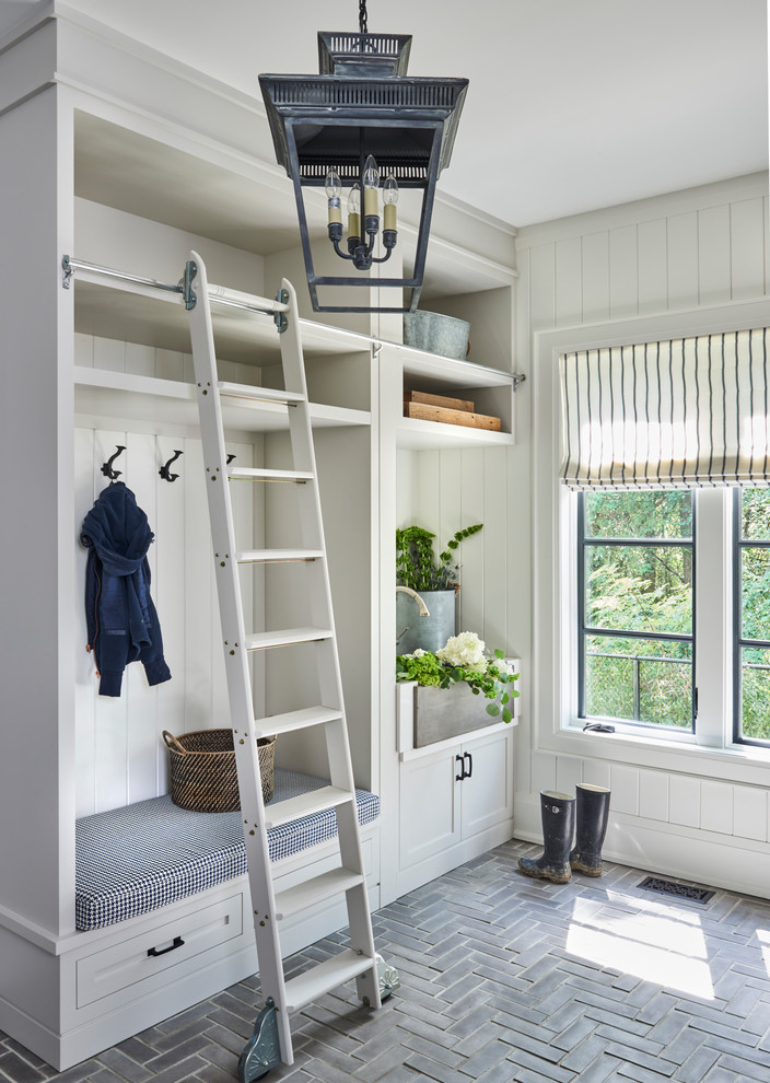 Design ideas for a large country mudroom in Toronto with white walls and brick floors.