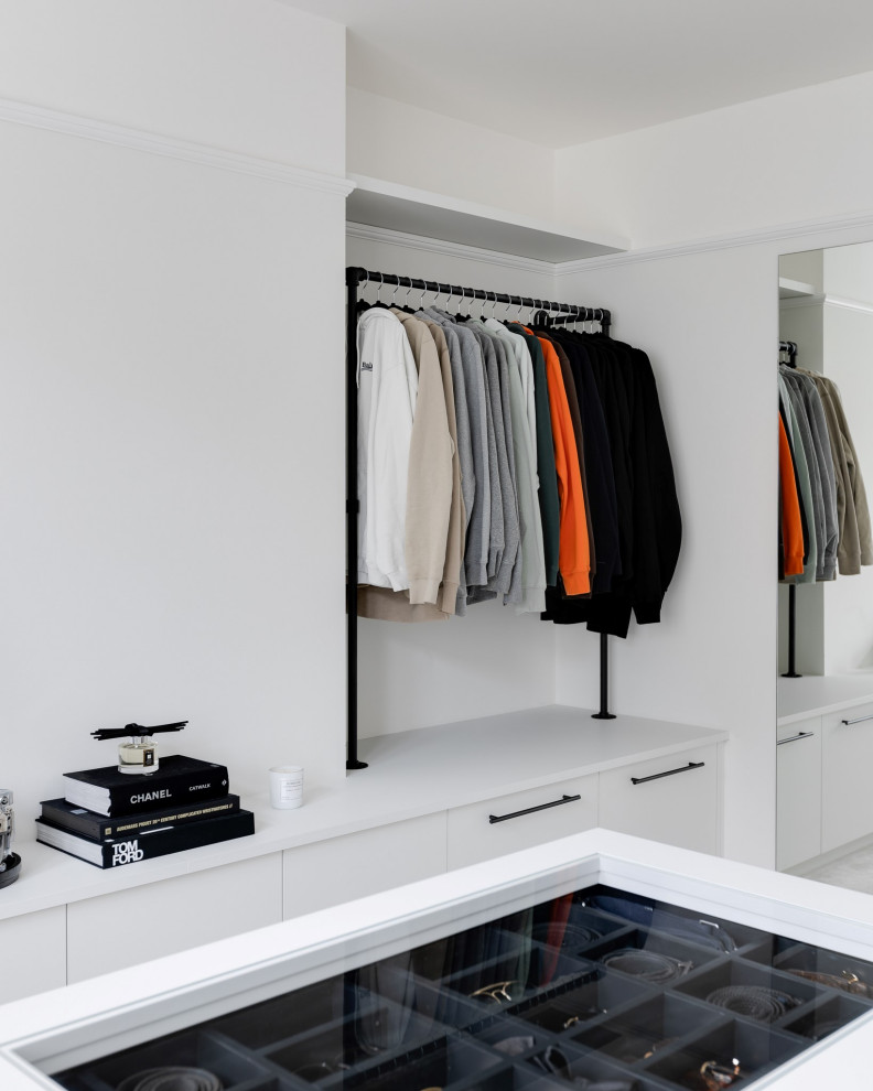 Medium sized modern walk-in wardrobe in Hertfordshire with flat-panel cabinets, white cabinets, carpet, grey floors and a feature wall.