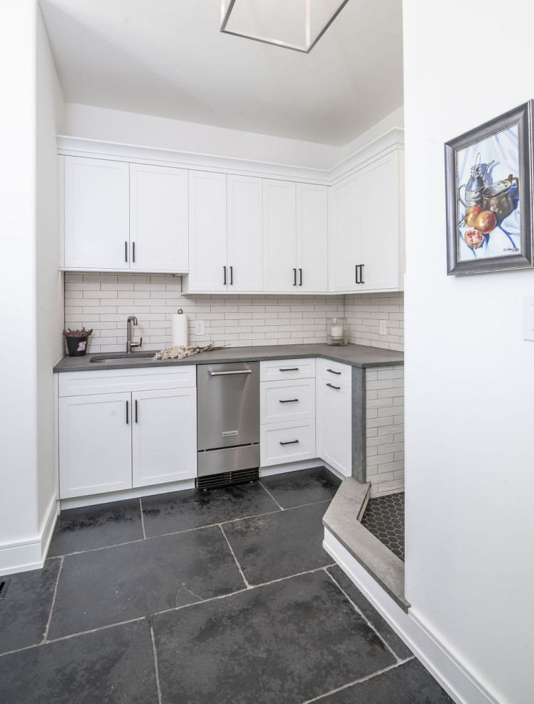 Inspiration for a modern utility room in Baltimore with an undermount sink, shaker cabinets, white cabinets, beige splashback, matchstick tile splashback, white walls, a side-by-side washer and dryer, black floor and grey benchtop.