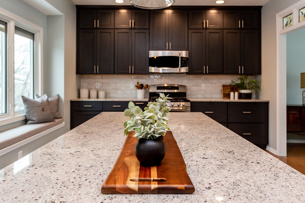 Large transitional u-shaped medium tone wood floor and brown floor eat-in kitchen photo with an undermount sink, recessed-panel cabinets, white cabinets, granite countertops, white backsplash, subway tile backsplash, stainless steel appliances, an island and gray countertops