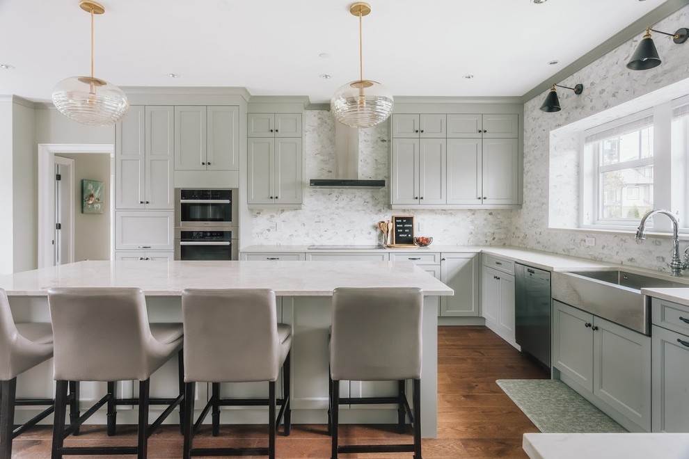 Photo of a modern l-shaped open plan kitchen in Vancouver with a drop-in sink, recessed-panel cabinets, grey cabinets, solid surface benchtops, multi-coloured splashback, stone tile splashback, plywood floors, with island, brown floor and white benchtop.