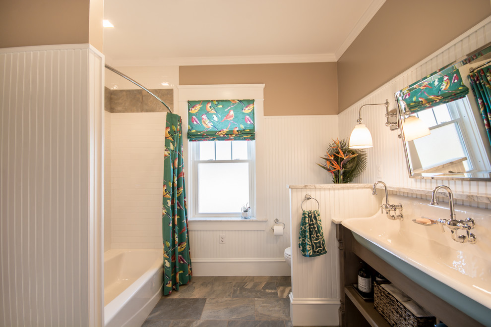 Design ideas for a large traditional kids bathroom in Providence with furniture-like cabinets, distressed cabinets, marble benchtops, gray tile, porcelain tile, an alcove tub, a shower/bathtub combo, a two-piece toilet, a trough sink, beige walls and porcelain floors.