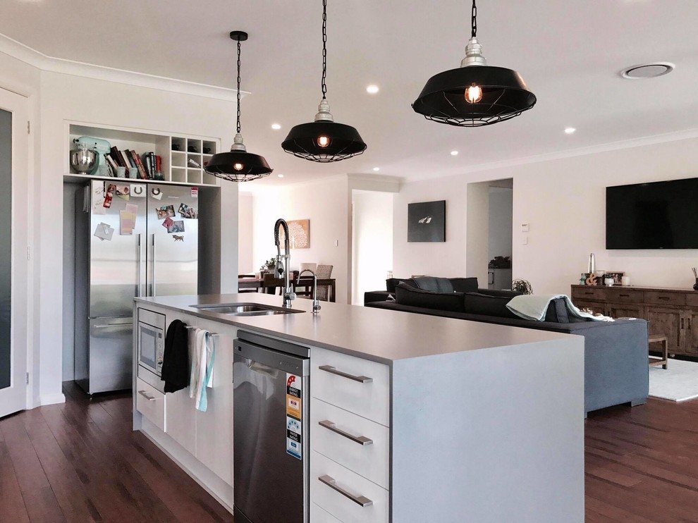 Design ideas for a large contemporary galley open plan kitchen in Sydney with an undermount sink, flat-panel cabinets, white cabinets, concrete benchtops, white splashback, stainless steel appliances, bamboo floors and with island.