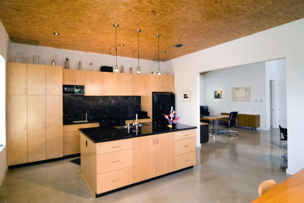 This is an example of a modern single-wall kitchen pantry in Houston with an undermount sink, flat-panel cabinets, light wood cabinets, black splashback, black appliances, concrete floors and with island.