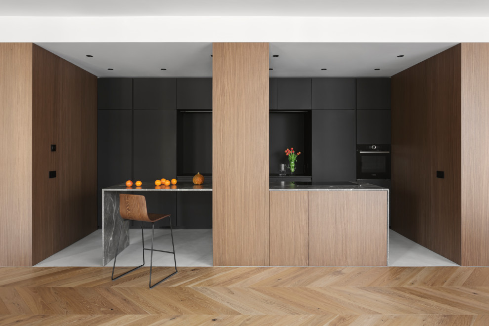 This is an example of a large modern galley open plan kitchen in Milan with flat-panel cabinets, dark wood cabinets, marble worktops, black splashback, stainless steel appliances, concrete flooring, multiple islands, grey floors and grey worktops.