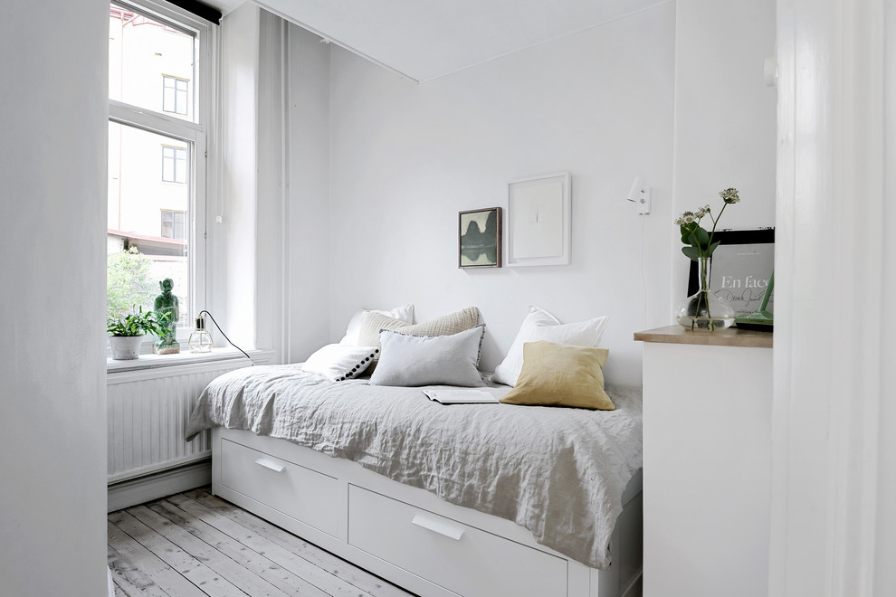 This is an example of a small scandinavian bedroom in Gothenburg with white walls, light hardwood floors and beige floor.