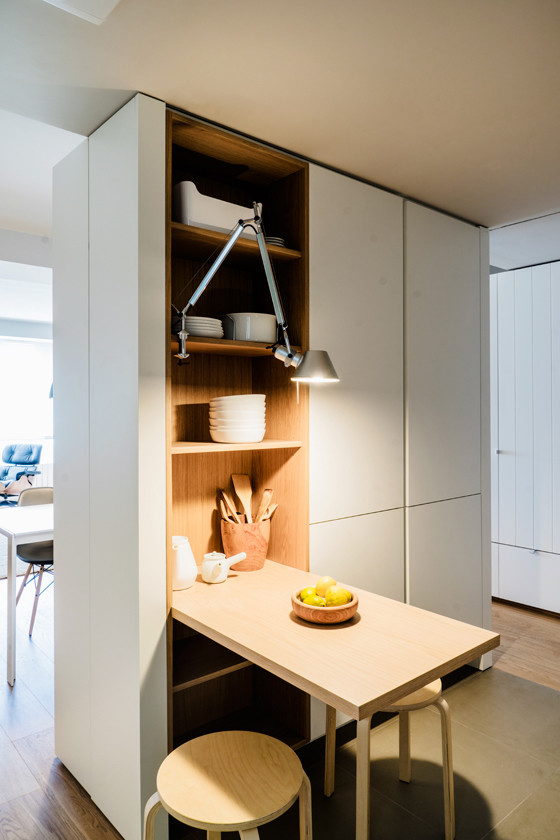 Small scandinavian l-shaped open plan kitchen in Madrid with an undermount sink, flat-panel cabinets, white cabinets, quartz benchtops, white splashback, glass sheet splashback, panelled appliances, ceramic floors and no island.