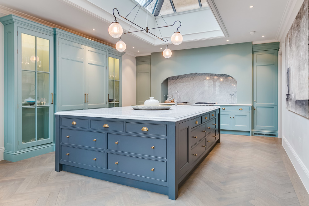 Inspiration for a mid-sized traditional l-shaped kitchen in London with beaded inset cabinets, turquoise cabinets, grey splashback, light hardwood floors, with island, beige floor and grey benchtop.