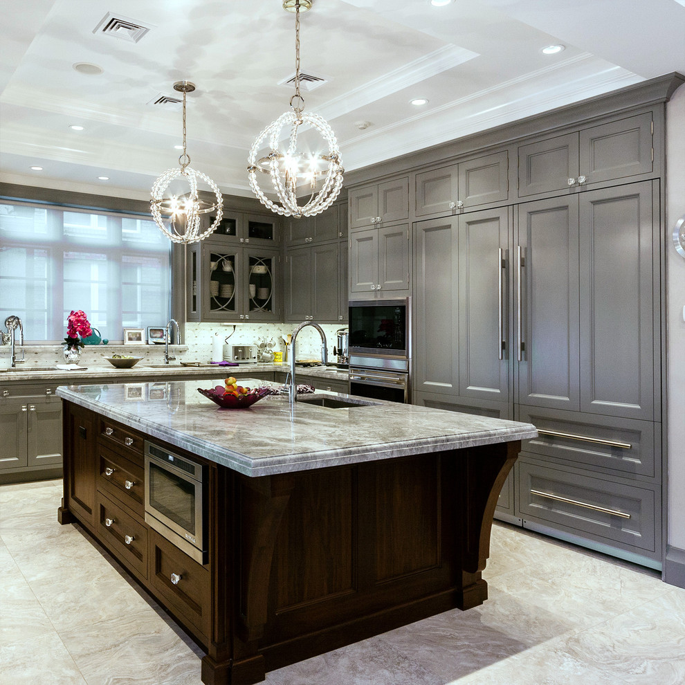 Photo of a large traditional kitchen in New York with panelled appliances, recessed-panel cabinets, grey cabinets, marble benchtops, with island, an undermount sink, grey splashback and white floor.