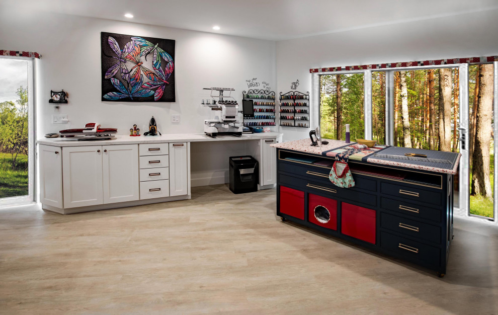 This is an example of a large transitional craft room in Orange County with white walls, vinyl floors, a built-in desk and brown floor.