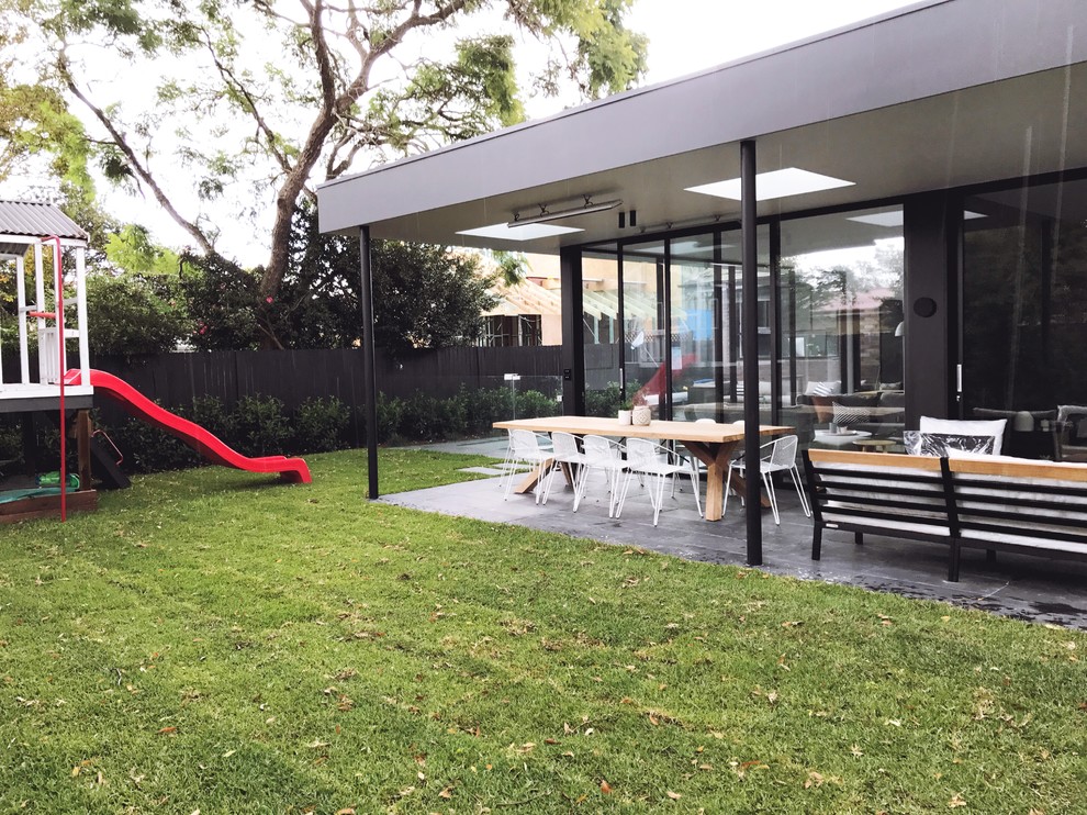 Photo of a mid-sized contemporary backyard partial sun xeriscape in Sydney with with outdoor playset and natural stone pavers.