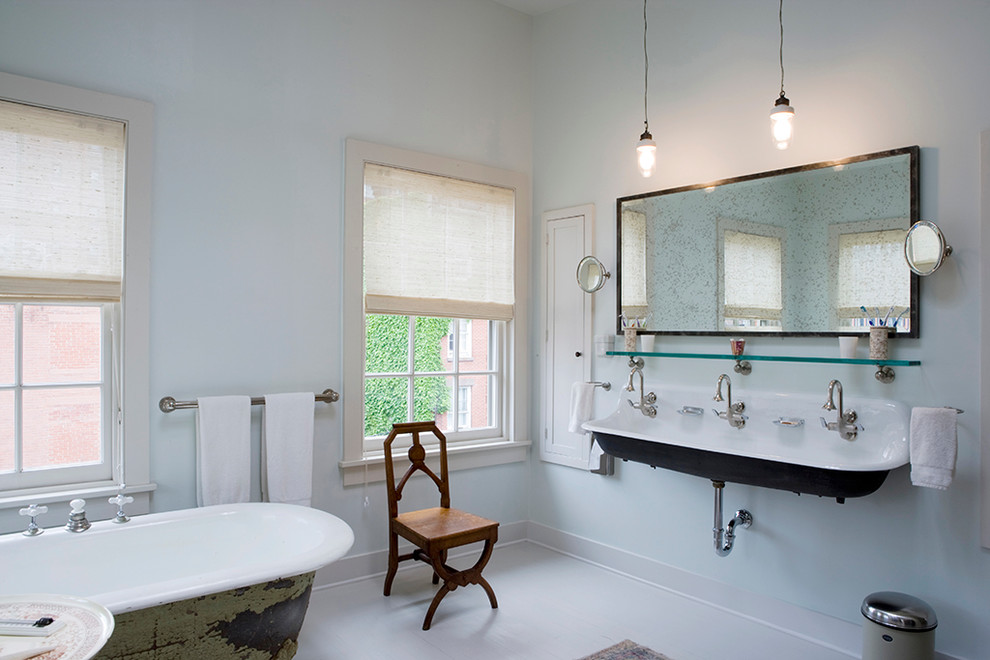 Photo of a transitional bathroom in New York with a trough sink, a claw-foot tub and blue walls.