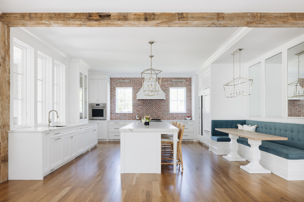 South Coast Farmhouse - Reclaimed Wisconsin barn beams delineating spaces for the kitchen and living areas. A unique, white-washed brick kitchen backsplash and banquet eat-in seating area.