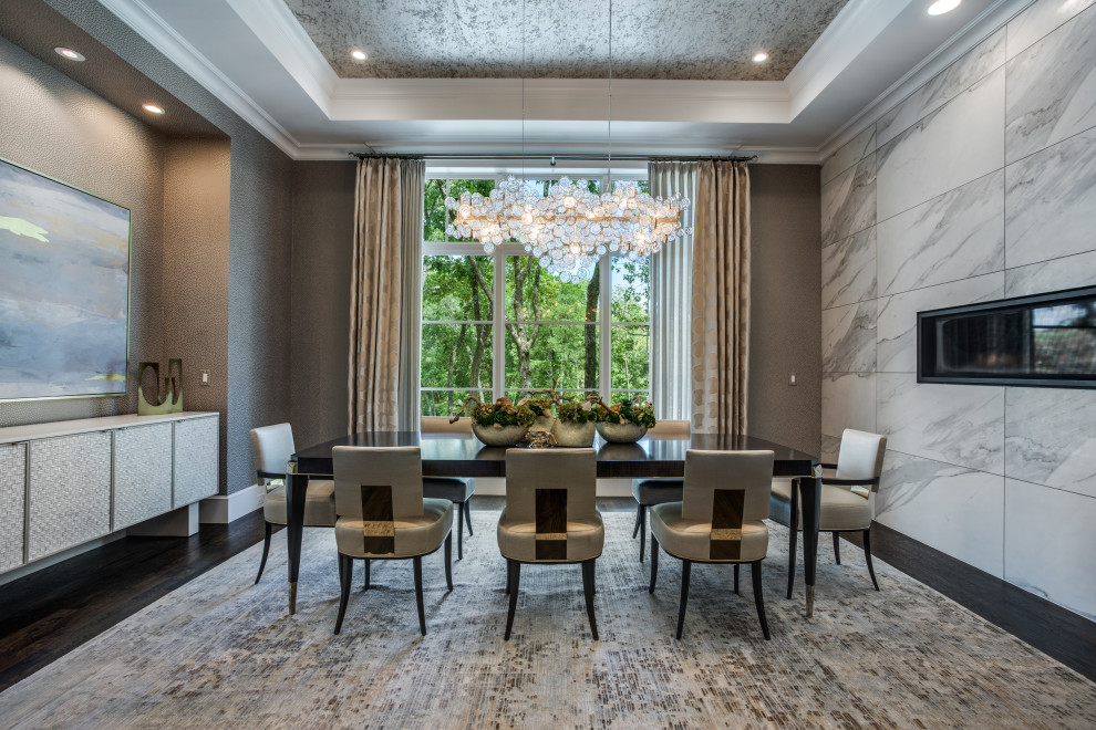 This is an example of a large transitional separate dining room in Dallas with metallic walls, medium hardwood floors, a ribbon fireplace, a tile fireplace surround, brown floor, recessed and wallpaper.