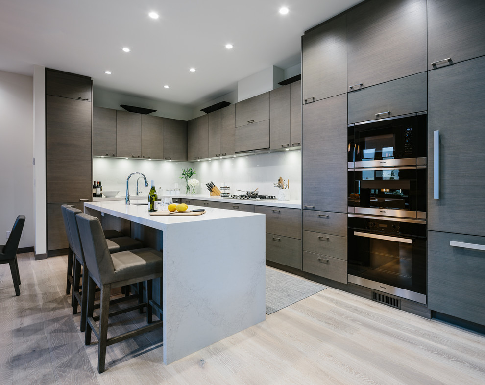 Inspiration for a large contemporary l-shaped eat-in kitchen in Vancouver with an undermount sink, flat-panel cabinets, dark wood cabinets, quartzite benchtops, white splashback, stone slab splashback, panelled appliances, medium hardwood floors, with island and grey floor.