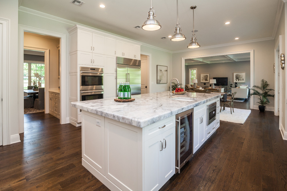 This is an example of a transitional u-shaped kitchen in New York with recessed-panel cabinets, white cabinets, marble benchtops, white splashback, stainless steel appliances, medium hardwood floors and with island.