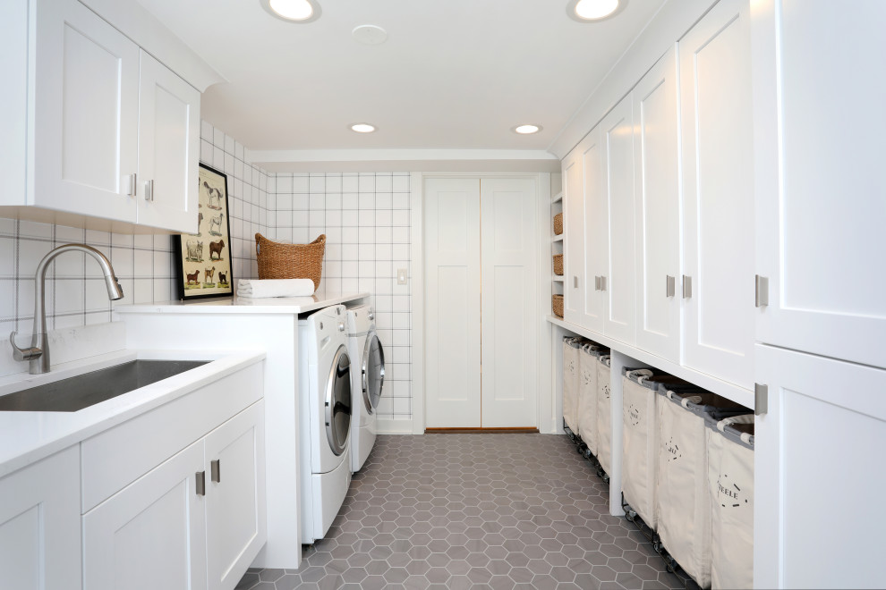 Design ideas for a transitional galley dedicated laundry room in Chicago with white walls, porcelain floors, grey floor, an undermount sink, shaker cabinets, white cabinets, a side-by-side washer and dryer, white benchtop and wallpaper.
