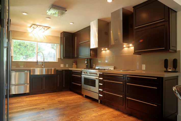 Example of a mid-sized minimalist u-shaped dark wood floor and beige floor enclosed kitchen design in Orange County with a farmhouse sink, recessed-panel cabinets, dark wood cabinets, stainless steel appliances, no island, quartz countertops, beige backsplash and stone slab backsplash