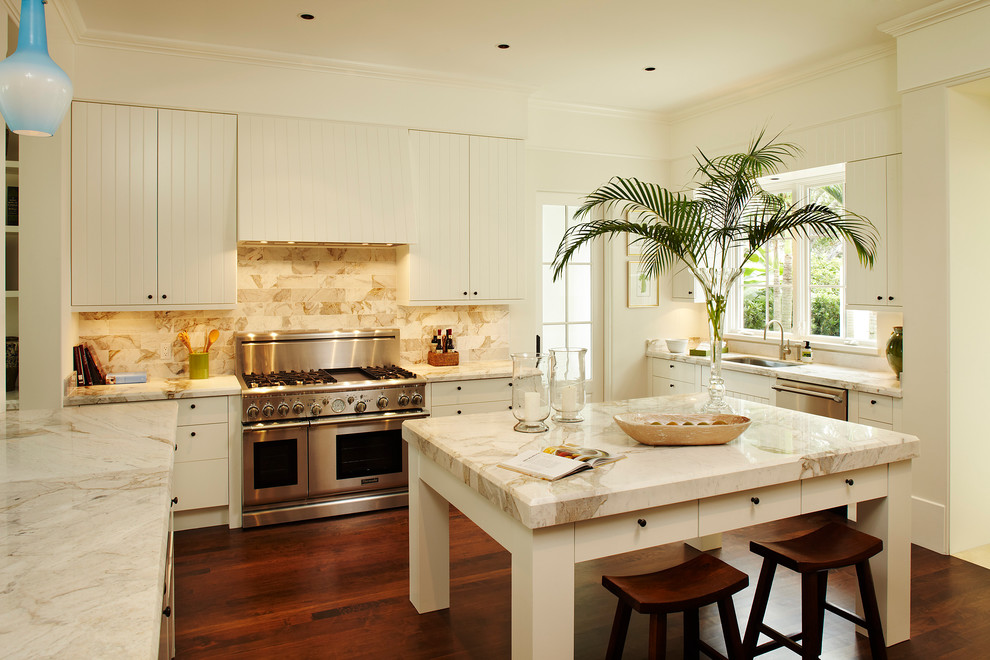 Mid-sized traditional u-shaped kitchen in Miami with stainless steel appliances, an undermount sink, white cabinets, marble benchtops, beige splashback, stone tile splashback, dark hardwood floors, with island, brown floor and beige benchtop.