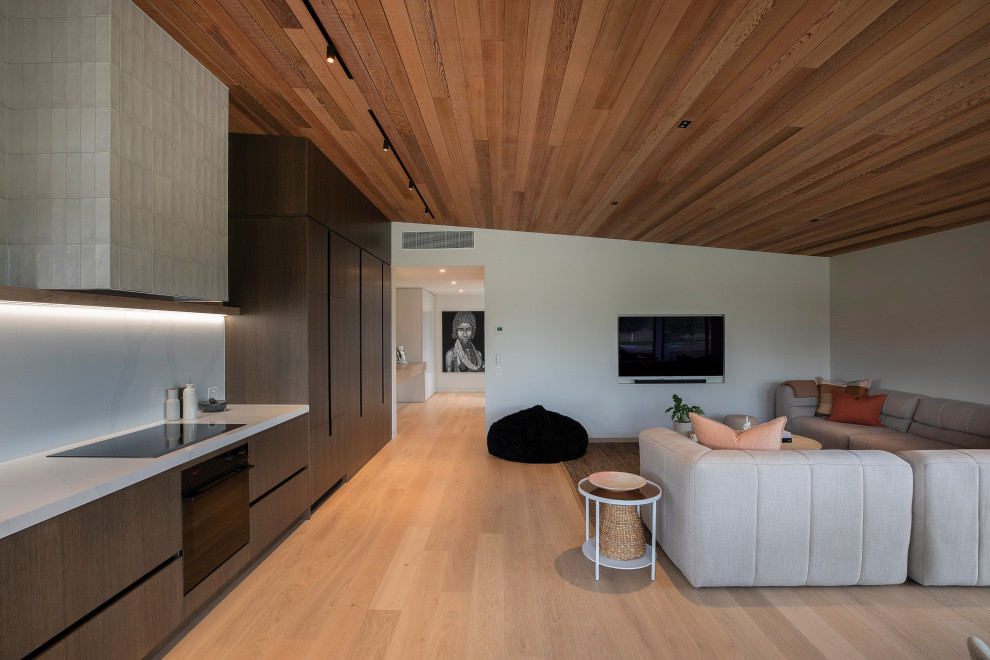 Photo of a Small modern Loft-style living room With White Walls, Light Hardwood Floors, a Wall-mounted TV, Beige Floor and Timber.