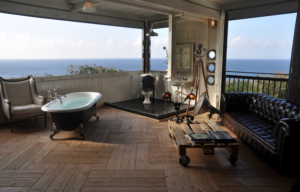 Photo of a large asian bathroom in Fukuoka with a freestanding tub, an open shower, black tile, light hardwood floors and a console sink.