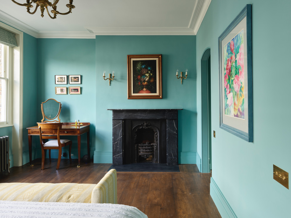 Aménagement d'une grande chambre parentale victorienne avec un mur bleu, parquet foncé, une cheminée standard, un manteau de cheminée en pierre et un sol marron.