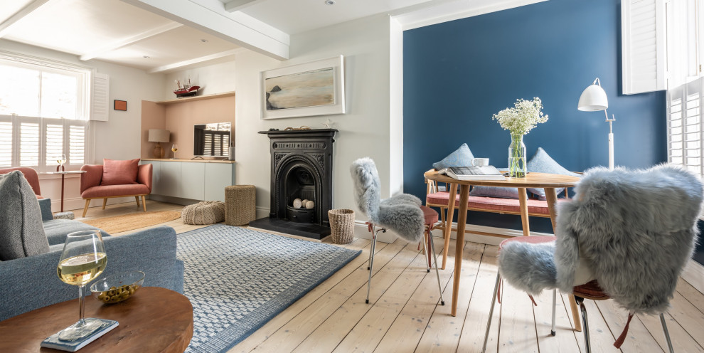 Imagen de salón abierto nórdico pequeño con paredes azules, suelo de madera clara, todas las chimeneas, marco de chimenea de metal, televisor independiente y vigas vistas