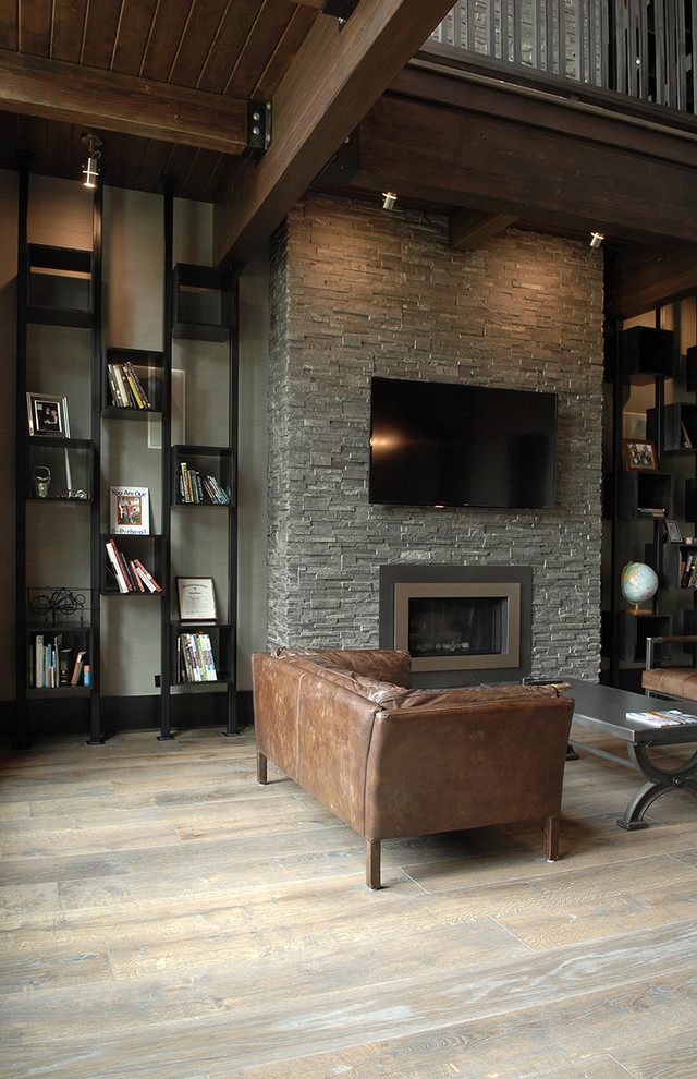 Photo of an expansive industrial study room in Chicago with white walls, medium hardwood floors, a standard fireplace, a stone fireplace surround, a freestanding desk, brown floor and exposed beam.