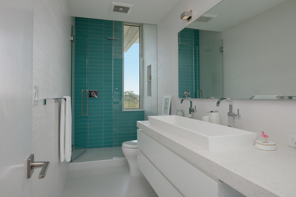 This is an example of a mid-sized beach style kids bathroom in Tampa with flat-panel cabinets, white cabinets, an alcove shower, a two-piece toilet, multi-coloured tile, glass tile, multi-coloured walls, porcelain floors, a vessel sink, quartzite benchtops, white floor, a hinged shower door and multi-coloured benchtops.