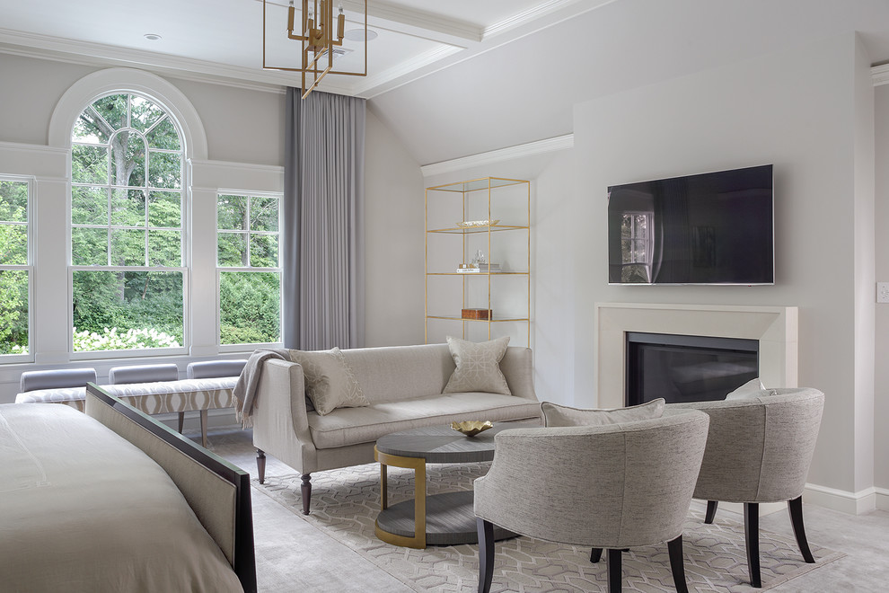 This is an example of a large traditional master bedroom in New York with grey walls, carpet, a standard fireplace, a plaster fireplace surround and beige floor.