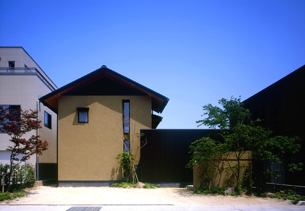 Asian two-storey stucco brown house exterior in Other with a gable roof and a metal roof.